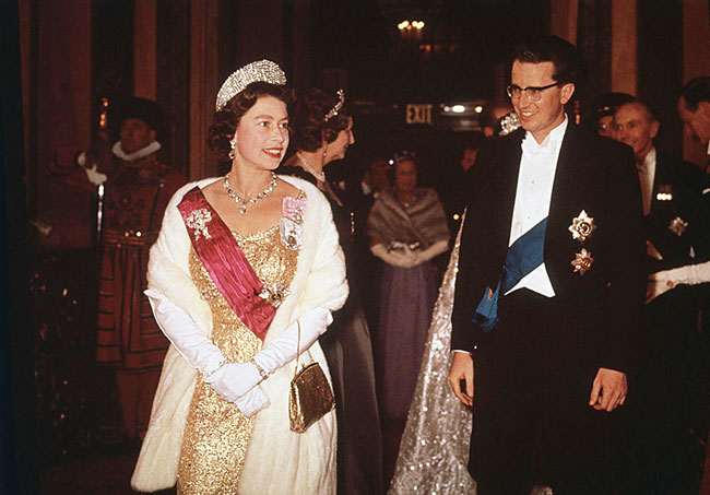 Королева Елизавета II в золотом вечернем платье, белой меховой накидке и элегантных перчатках